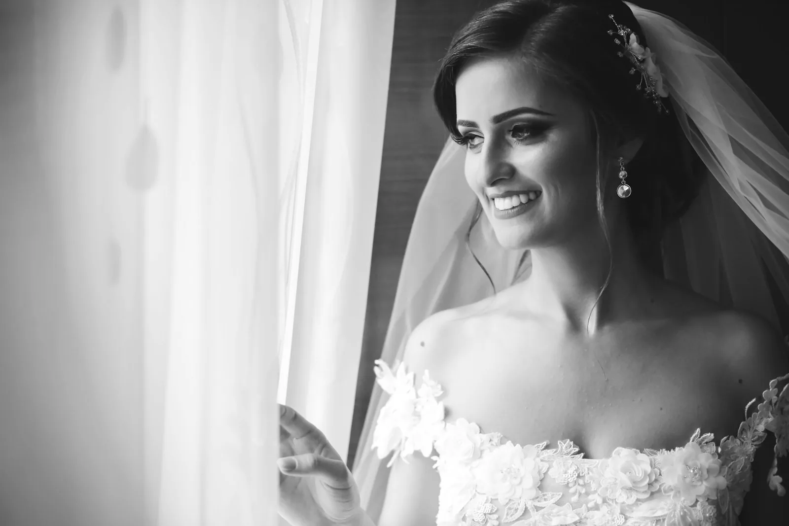 Novia sonriendo junto a la ventana antes de la ceremonia